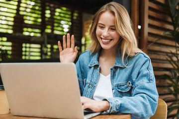 Portrait of caucasian happy woman making video call on laptop in cafe outdoors