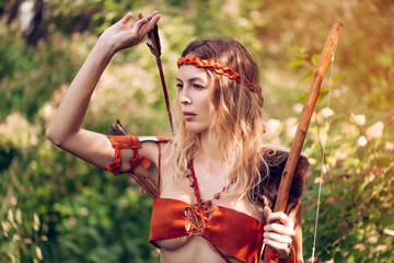Beautiful girl archer with long blond hair with a bow and arrows dressed in leather