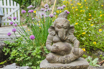 Ganesh stone statue in a springtime garden