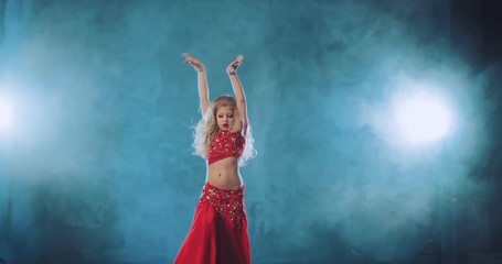Beautiful girl blonde with long hair dancing belly dance in tubers of smoke. Shaking belly. Pretty girl smiles and moves her body beautifully.