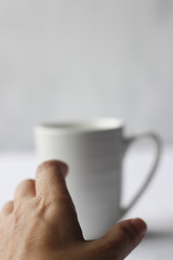 Coffee addiction, white coffee mug and hand