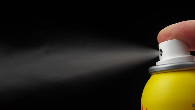 Slow motion of spray bottle drops on black background. Male perfume bottle on a dark background