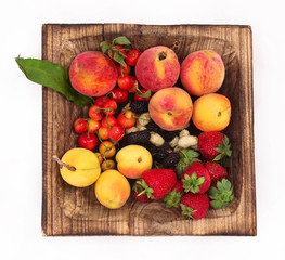 Summer fruits on a wooden plate. Along with fine droplets of water.