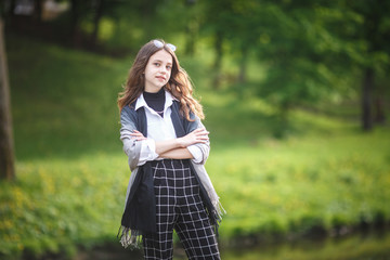 portrait of little beautiful stylish kid girl in city park on green forest background