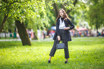portrait of little beautiful stylish kid girl in city park on green forest background