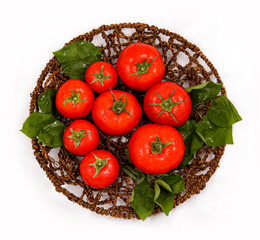 Fresh tomatoes on a basket and a wooden board. Along with water droplets.
