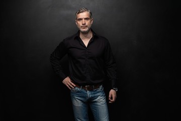 Obraz premium Middle-aged good looking man posing in front of a black background with copy space.