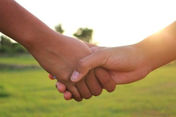 Children hold hands to show friendship, shoot blurred images, golden yellow light in the evening