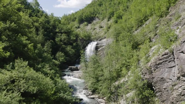 Aerial shot of drone rising over Secchiello stream in Val d&rsquo;Asta in Reggio Emilia in Italy flying towards Golfarone Waterfall.