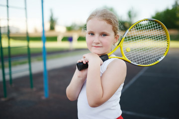 happy girl plays tennis on court outdoors