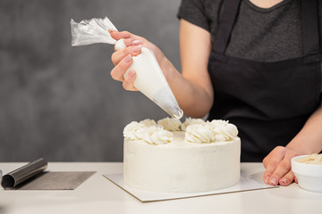 Confectioner at work. Cream cake decorating. Cook table preparing a cake.