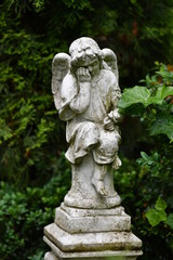Fototapeta na wymiar A white, weathered statue of a sad angel on a christian cemetery in Berlin-Germany.