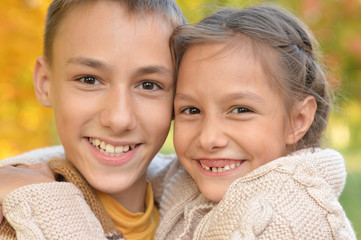 Portrait of brother and sister hugging in autumnal park