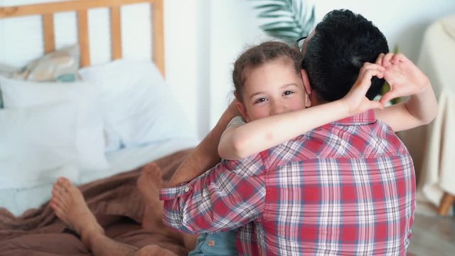 Dad hugs and kisses his daughter, girl shows heart with hands, slow motion