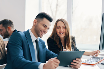 Smiling successful business people discussing ideas using digital tablet in office