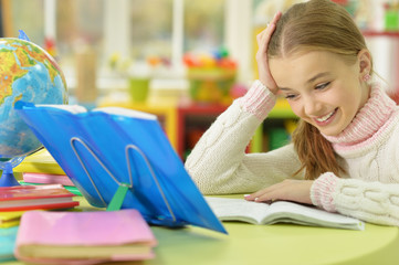 Cute girl leaning on hand while doing her homework