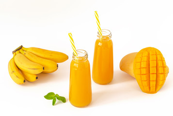 Healthy mango smoothie in a glass with mint and straw isolated on white. Refreshing and tasty smoothies with tropical fruits: mango and banana.