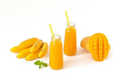 Fresh mango banana smoothie in a glass with mint on white. Refreshing and tasty smoothies with tropical fruits: mango and banana.