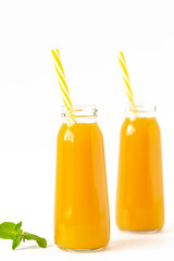 Healthy mango smoothie in a glass with mint and straw isolated on white. Refreshing and tasty smoothies with tropical fruits: mango and banana.