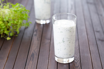 Fresh homemade yogurt (kefir, ayran) in glass with herbs. Ayran, homemade yogurt drink with herbs and cucumbers - healthy summer refreshing cold drink. Probiotic fermented dairy drink. Healthy food. 