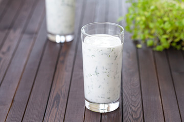 Fresh homemade yogurt (kefir, ayran) in glass with herbs. Ayran, homemade yogurt drink with herbs and cucumbers - healthy summer refreshing cold drink. Probiotic fermented dairy drink. Healthy food. 