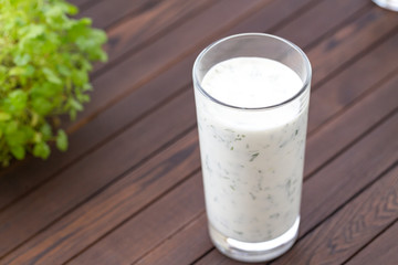 Fresh homemade yogurt (kefir, ayran) in glass with herbs. Ayran, homemade yogurt drink with herbs and cucumbers - healthy summer refreshing cold drink. Probiotic fermented dairy drink. Healthy food. 