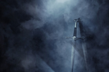 mysterious and magical photo of silver sword over gothic black background with smoke. Medieval period concept
