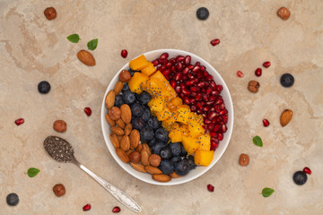 Top view of a smoothie bowl with fresh ripe blueberry, nuts, chia, mango and pomegranate. The concept of healthy eating and lifestyle.  