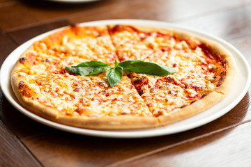 Margherita pizza on wooden background. Italian pizza with mozzarella, cheese and basil leaves. 