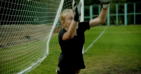 Young teenager girl soccer goalie diving to catch the ball during a match or practice. 4K UHD - Powered by Adobe