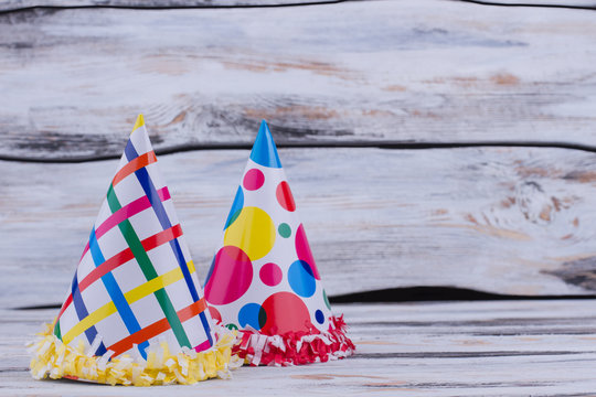 Funny party cone hats on wooden boads. Birthday carton party caps on wooden table with text space.