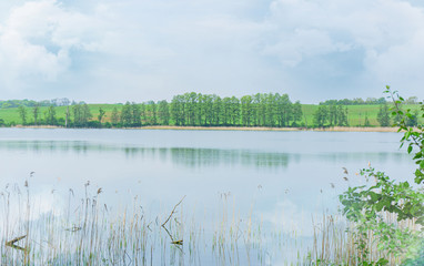 Beautiful view of the lake, sky, trees and water grass. Spring, Mazury, Poland.