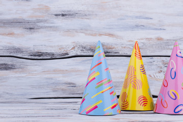 Various party hats on wooden background. Three festive Birthday caps on rustic wooden surface with copy space.