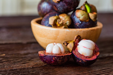 Mangosteen fruit in wooden bowl on dark wooden table close up