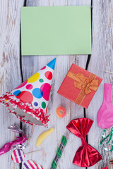 Party accessories and blank paper card. Colorful Birthday items and blank paper sheet for greeting. Concept of childs Birthday celebration.