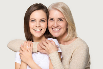 Headshot portrait attractive grandmother and granddaughter embracing looking at camera