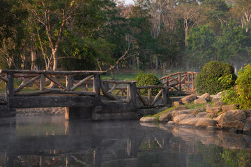 Bridge with pond in a park at evening time.