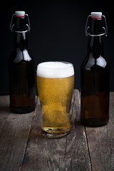 glass of lager beer and a bottle on a dark background