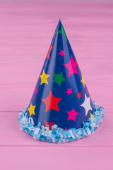 Funny party hat for kids. Cardboard party cap on color wood background, vertical image. Handmade accessory for party celebration.