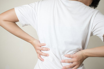 Closeup view of young women with muscular pain in her back, caused by heavy lifting, the concept of musculoskeletal system, spinal diseases.