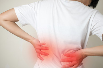 Closeup view of young women with back pain in the muscles which is caused by heavy lifting, the concept of musculoskeletal system.