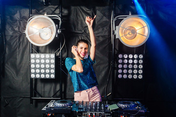 Fototapeta na wymiar Hispanic dj woman having fun playing music on deck at club nightlife lifestyle. Female dj mixing music on black background with bright lighting with lights. Party, technology and people concept