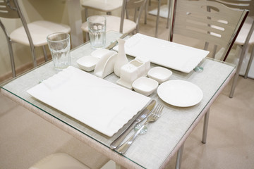 Dining table with appliances, plates and glasses