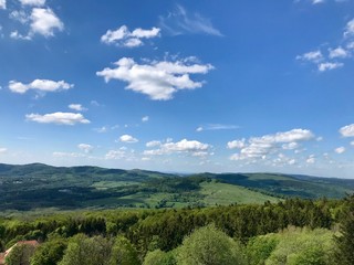 Scenic hike to the Kreuzberg (Calvary) in the Bavarian Rhoen region (Germany) on a beautiful sunny summer day through lush green landscape with grass, trees and a blue sky with white clouds