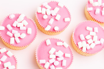 Colorful cupcakes on a pink background.