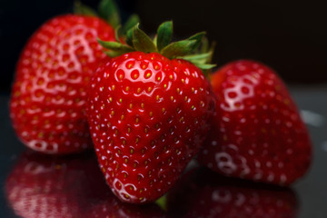 Strawberry closeup. Macro image of fresh strawberries on dark background