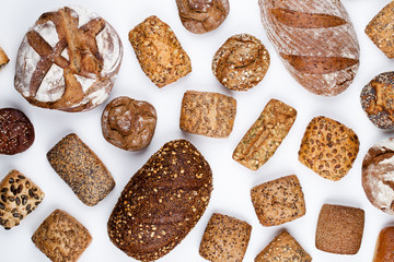 Gold rustic crusty loaves of bread and buns on wooden background. Still life captured from above top view, flat lay.