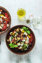 Italian traditional Tuscan panzanella salad with fresh tomatoes and cheese in clay plates and white wine in a bottle and glasses . authentic Mediterranean healthy food