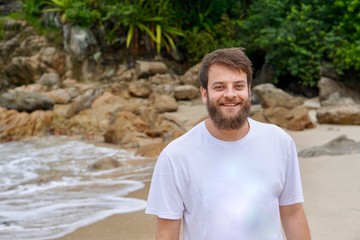 Close up portrait of a Brazilian man with blue eyes and a beard smiling on the beach