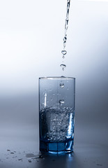 pouring fresh drink water to blue glass